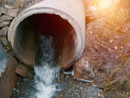 Wastewater sewage flows from a pipe into the river. Tackling Pollution. Managing Wastewater and River Ecology. Bad smell toxic water.