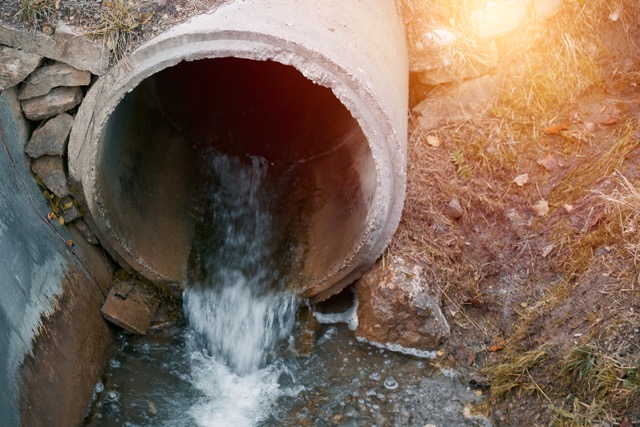 Wastewater sewage flows from a pipe into the river. Tackling Pollution. Managing Wastewater and River Ecology. Bad smell toxic water.